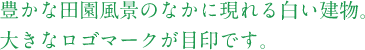 豊かな田園風景のなかに現れる白い建物。 大きなロゴマークが目印です。 